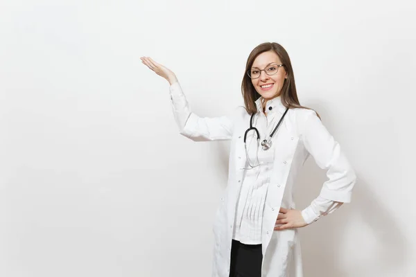 Uśmiechnięta kobieta młody lekarz z stetoskop, izolowana na białym tle okulary. Lekarka w medycznych suknia, wskazując ręką na bok na miejsce. Pracowników służby zdrowia, zdrowia, medycyny pojęcie. — Zdjęcie stockowe