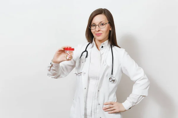 Sonriente mujer doctora joven y segura de sí misma con estetoscopio, gafas aisladas sobre fondo blanco. La doctora en bata médica sostiene la botella con pastillas. Personal sanitario, concepto de medicina . — Foto de Stock
