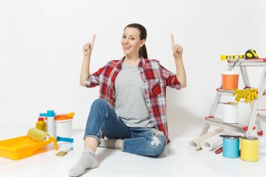 Kadın işaret işaret parmakları kadar kopya alanı üzerinde beyaz arka plan üzerinde izole yenileme daire için aygıtlar ile yere otur. Duvar kağıdı, yapıştırma, boyama araçları için aksesuarlar. Onarım kavramı