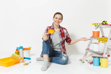 Beyaz arka plan üzerinde izole yenileme daire için aygıtlar ile katta oturan para ile kredi kartı tutan sevimli kadın. Boyama araçları yapıştırma için aksesuarları duvar kağıdı. Onarım ev concept.