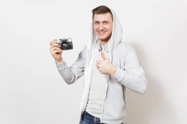 Genç yakışıklı gülümseyen adam öğrenci tişört ve kulaklık ile hood ile hafif kazak retro kamera tutan ve beyaz arka plan üzerinde izole jest başparmak gösterir. Genel kavram-in fotoğraf, hobi
