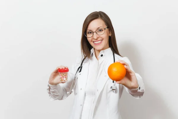 Sonriente joven doctora confiada con estetoscopio, gafas aisladas sobre fondo blanco. La doctora en bata médica sostiene la botella con pastillas, naranja. Personal sanitario, concepto de medicina . — Foto de Stock