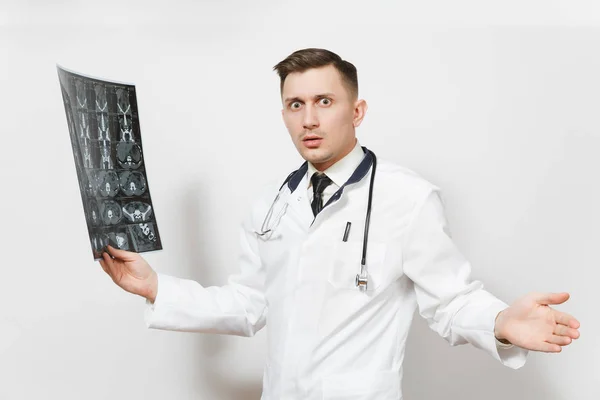 Шокований красивий молодий лікар тримає рентгенівське рентгенографічне зображення Кет сканування мрі ізольовано на білому тлі. Чоловік-лікар у медичній формі, стетоскоп. Медичний персонал, охорона здоров'я, концепція медицини . — стокове фото