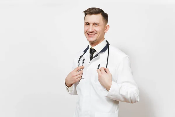 Sonriendo confiado experimentado guapo joven médico aislado sobre fondo blanco. Médico en uniforme médico, cámara con aspecto de estetoscopio. Personal sanitario, salud, concepto de medicina . — Foto de Stock