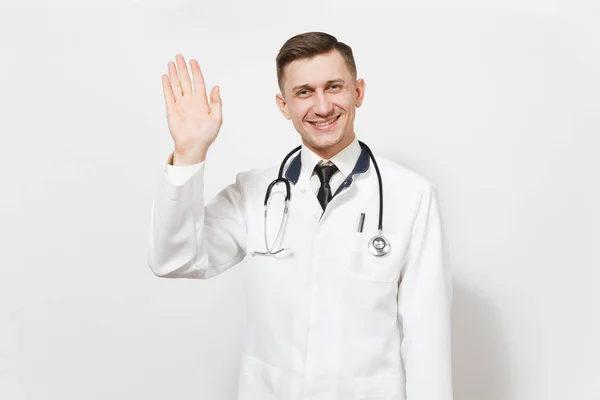 Uśmiechający się zadowolony przystojny młody lekarz mężczyzna na białym tle. Lekarz mężczyzna w medycznych jednolite, stetoskop wyglądający aparat, machając ręką na powitanie. Koncepcja medycyna zdrowia pracowników służby zdrowia — Zdjęcie stockowe