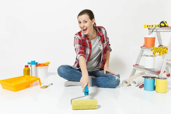 Γυναίκα σε casual ρούχα που κάθεται στο πάτωμα με κυλινδρικό χρωστήρα, όργανα για διαμέρισμα ανακαίνιση που απομονώνονται σε λευκό φόντο. Ταπετσαρία, αξεσουάρ για την κόλληση, εργαλεία ζωγραφικής. Επισκευή concept home. — Φωτογραφία Αρχείου