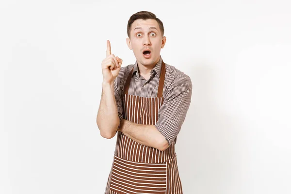 Молодий шеф-кухар або офіціант в смугастому коричневому фартусі, сорочка тримає індексний палець з великою новою ідеєю ізольовано на білому тлі. Чоловік-домогосподарка або працівник. Домашній працівник для реклами . — стокове фото