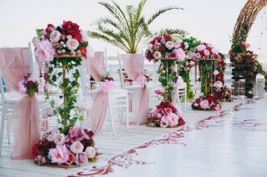 Güzel dekorasyon düğün töreni pembe, Bordo ve beyaz tonlarda ahşap iskele üzerinde. Sandalye dekore edilmiş ince bir bez, boncuk ve gül ve peonies çiçek kompozisyonlar