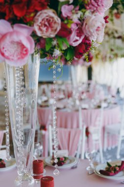 Güzel dekorasyon düğün Ziyafet pembe, Bordo ve beyaz tonlarda tentenin altında. Bir büyük çiçek düzenleme ile yüksek vazo Ziyafet salonunda yemek masası üstündeki dekore