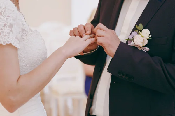 美しい結婚式のお祝い。青いスーツとブートニ エールと白いシャツで新郎を置く光のインテリアでエレガントなレースで彼の花嫁ドレス半袖婚約指輪 — ストック写真