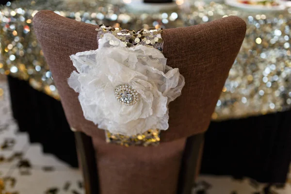 Hermosa decoración de un lujoso banquete de bodas en un restaurante de estilo retro. Sillón con un paño marrón con una gran decoración en forma de flor blanca con encaje, pedrería y lentejuelas — Foto de Stock