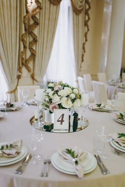 Bela decoração de um banquete de casamento em um restaurante em cores pastel. Decoração de vaso de mesa de jantar de banquete com arranjo de flores, castiçal, cartão com número de tabela no quadro — Fotografia de Stock