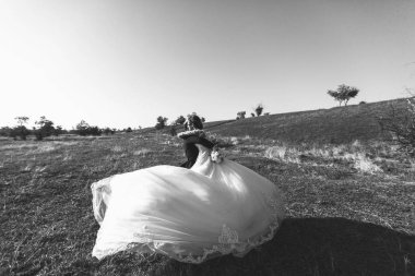 Güzel düğün photosession. Yakışıklı damat takım elbise ve dantel elbise gökyüzüne karşı büyük alanı etrafında bir yürüyüş için mükemmel saç modeli ile onun silah genç gelin çember gözlük. Siyah ve beyaz
