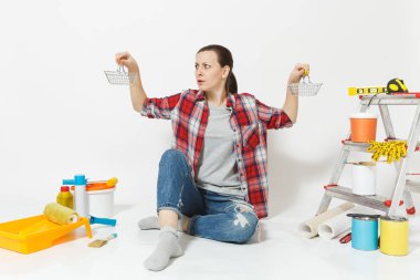 Şok üzgün üzgün kadın metal bakkal alışveriş sepetleri tutar. Beyaz arka plan üzerinde izole yenileme daire için aygıtlar. Duvar kağıdı, aksesuarlar, resim için araçlar. Onarım ev concept.