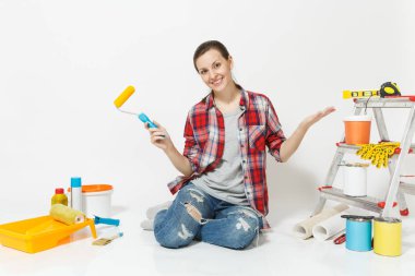 Rahat kıyafetler kat boya silindiri ile beyaz arka plan üzerinde izole yenileme daire için aygıtlar üzerinde oturan kadın. Duvar kağıdı, yapıştırma, boyama araçları için aksesuarlar. Onarım ev concept.