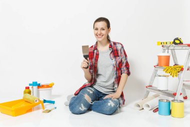 Rahat kıyafetler macun spatulası, yenileme daire oda için aygıtlar ile katta oturan kadın beyaz arka plan üzerinde izole. Boyama araçları yapıştırma için aksesuarları duvar kağıdı. Onarım ev concept.