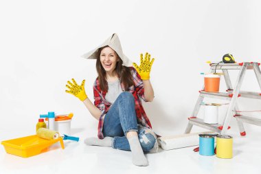 Gazete şapka, sarı eldiven beyaz arka plan üzerinde izole yenileme daire için aygıtlar ile katta oturan güzel kadın. , Duvar kağıdı yapıştırma aksesuarları, boyama araçlarını. Onarım ev concept