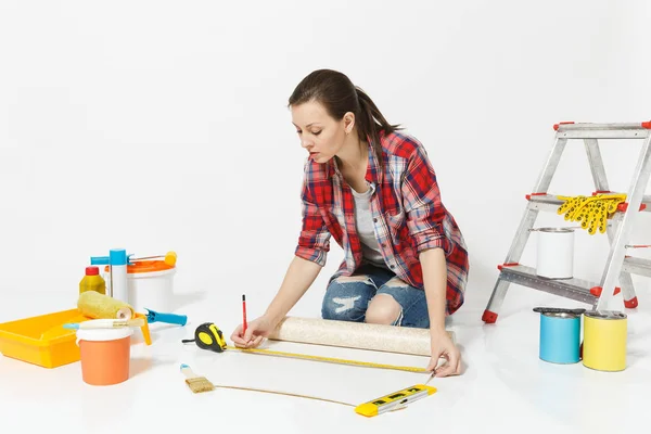 Woman sitting on floor with wallpaper rolls, measure tape, instruments for renovation apartment isolated on white background. Accessories for gluing, painting tools. Repair home concept. Copy space. — Stock Photo, Image