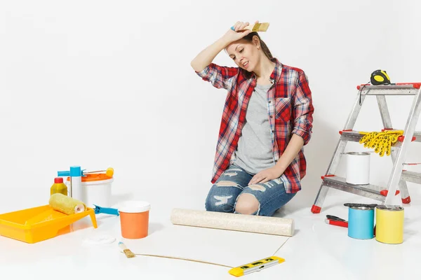Woman in casual clothes sitting on floor with wallpaper rolls, brush, instruments for renovation apartment isolated on white background. Accessories for gluing, painting tools. Repair home concept. — Stock Photo, Image