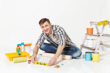 Kabarcık ruh düzeyi, beyaz arka plan üzerinde izole yenileme daire için aygıtlar bina duvar kağıdı rulo, katta oturan bir genç adam. Aksesuarlar, boyama araçlarını yapıştırma. Onarım ev concept