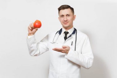 Beyaz arka plan üzerinde izole gülümseyen yakışıklı genç doktor adam. Kırmızı elma tutan tıbbi üniforma stetoskop erkek doktor. Sağlık personeli Sağlık Tıp kavramı. Doğru beslenme. Kopya alanı