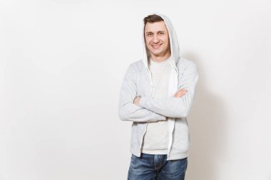 T-shirt ve kukuleta ile hafif kazak genç gülümseyen yakışıklı kollarını göğüs üzerinde çarpı işareti üzerinde izole beyaz arka plan sevinir. Duygular, iyi bir ruh hali kavramı. Kopya alanı reklam için.