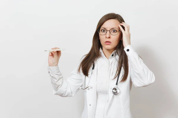 Sorprendido triste molesto joven médico mujer en bata médica con estetoscopio, gafas, termómetro clínico con alta temperatura de la fiebre aislada sobre fondo blanco. Personal sanitario, concepto de medicina . — Foto de Stock