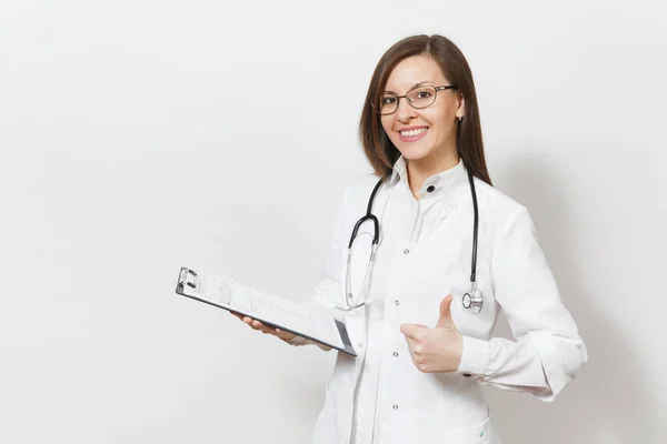 Giovane donna medico sorridente con stetoscopio, occhiali che mostrano i pollici in alto isolati su sfondo bianco. Medico donna in abito medico in possesso di tessera sanitaria sulla cartella blocco note. Concetto di personale sanitario . — Foto Stock