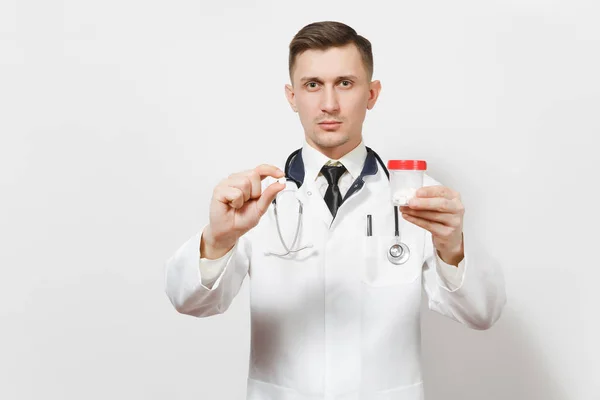 Grave esperto bel giovane medico isolato su sfondo bianco. Medico maschio in uniforme medica, stetoscopio contenente flacone con pillole bianche. Personale sanitario, salute, concetto di medicina . — Foto Stock