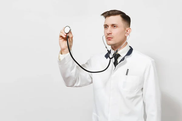 Grave fiducioso esperto bel giovane medico isolato su sfondo bianco. Medico maschio in uniforme medica che utilizza e mostra lo stetoscopio. Personale sanitario, salute, concetto di medicina . — Foto Stock