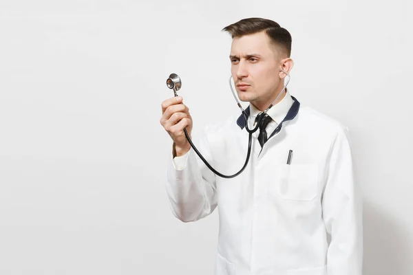 Grave fiducioso esperto bel giovane medico isolato su sfondo bianco. Medico maschio in uniforme medica che utilizza e mostra lo stetoscopio. Personale sanitario, salute, concetto di medicina . — Foto Stock