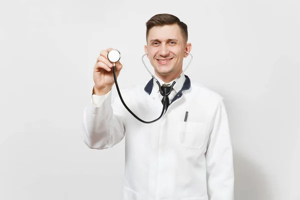 Sorridente fiducioso esperto bel giovane medico isolato su sfondo bianco. Medico maschio in uniforme medica che utilizza e mostra lo stetoscopio. Personale sanitario, salute, concetto di medicina . — Foto Stock