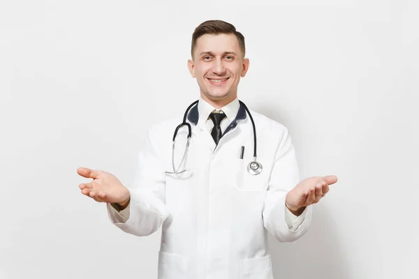 Smiling happy young doctor man isolated on white background. Male doctor in medical gown and stethoscope looking camera, spreading hands for greeting. Healthcare personnel, health, medicine concept. — Stock Photo, Image