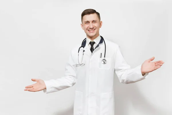 Smiling happy young doctor man isolated on white background. Male doctor in medical gown and stethoscope looking camera, spreading hands for greeting. Healthcare personnel, health, medicine concept. — Stock Photo, Image