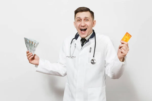 Щасливий молодий лікар ізольований на білому тлі. Чоловік-лікар в медичній уніформі стетоскоп тримає пакет доларів, банкноти готівкові гроші, кредитну картку. Концепція охорони здоров'я персоналу медицини . — стокове фото