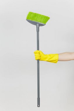 Kadın el sarı eldiven tutar uzun gri süpürge ile temizlik ve süpürme yeşil villus beyaz arka plan üzerinde izole kapatın. Temizlik malzemeleri kavramı. Kopya alanı reklam için