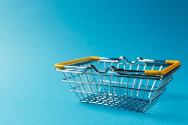 Metal Market sepeti indirdi kolları ve üzerinde mavi arka plan izole sarı plastik elemanları süpermarkette alışveriş için kapatın. Alışveriş kavramı. Kopya alanı reklam için