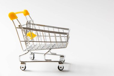 Süpermarket bakkal itme sepetinin siyah jantlar ve üzerindeki beyaz arka plan üzerinde izole sarı plastik öğelerle birlikte alışveriş için kapatın. Alışveriş kavramı. Kopya alanı reklam için