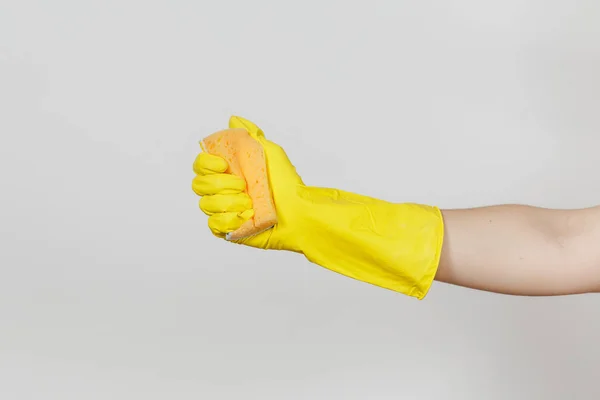 Nahaufnahme der weiblichen Hand in gelben Handschuhen hält und drückt gelb-orangefarbenen Schwamm zum Reinigen und Spülen von Geschirr isoliert auf weißem Hintergrund. Reinigungsmittelkonzept. Kopierfläche für Werbung — Stockfoto