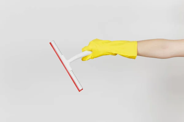 Close up da mão feminina em luvas amarelas horizontal mantém rodo branco para limpeza da superfície com elementos vermelhos isolados no fundo branco. Conceito de material de limpeza. Espaço de cópia para propaganda — Fotografia de Stock