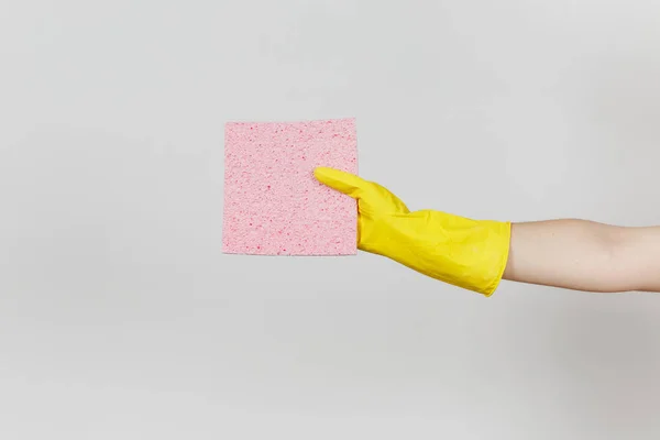 Il primo piano della mano femminile in guanti gialli tiene orizzontale il tovagliolo assorbente rosa per la pulizia e il lavaggio dei piatti isolati su sfondo bianco. Concetto di forniture di pulizia. Copia spazio per pubblicità — Foto Stock