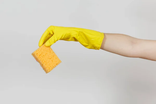 Primo piano di mano femminile in guanti gialli orizzontale tiene spugna giallo-arancio per la pulizia e il lavaggio dei piatti isolati su sfondo bianco. Concetto di forniture di pulizia. Copia spazio per pubblicità — Foto Stock