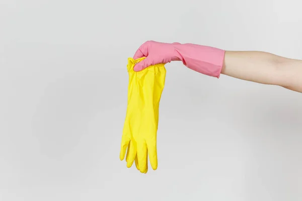 Close up da mão feminina em luvas cor-de-rosa segura um par de luvas amarelas de borracha para limpar e lavar pratos isolados em fundo branco. Conceito de material de limpeza. Espaço de cópia para propaganda — Fotografia de Stock