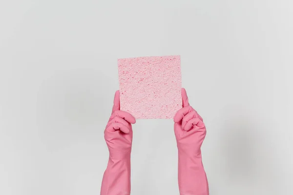 Крупним планом жіночі руки в рожевих рукавичках горизонтально тримає рожеву поглинаючу серветку для прибирання і миття посуду ізольовано на білому тлі. Концепція очищення приладів. Копіювати простір для реклами — стокове фото