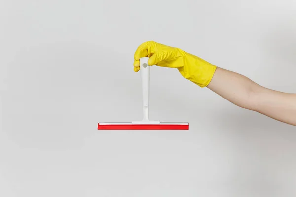 女性手的特写在黄色手套水平举行白色刮板为表面清洁与红色元素隔绝在白色背景。清洁用品的概念。复制广告空间 — 图库照片