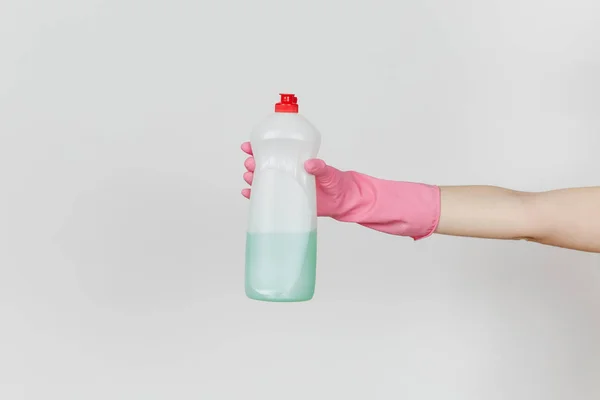 Primo piano di mano femminile in guanti rosa tiene bottiglia bianca con liquido detergente verde per lavare i piatti con posto per il testo isolato su sfondo bianco. Concetto di forniture di pulizia. Copia spazio per l'annuncio — Foto Stock