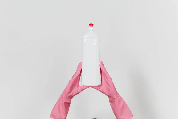 Крупним планом жіночі руки в рожевих рукавичках тримають білу пляшку з чистішою рідиною для миття посуду з місцем для тексту ізольованим на білому тлі. Концепція очищення приладів. Копіювати простір для оголошення — стокове фото
