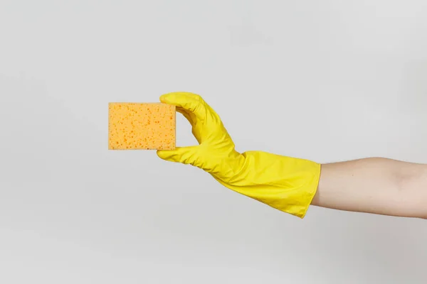 Close up de mão feminina em luvas amarelas horizontal detém esponja amarelo-laranja para a limpeza e lavagem de pratos isolados em fundo branco. Conceito de material de limpeza. Espaço de cópia para propaganda — Fotografia de Stock