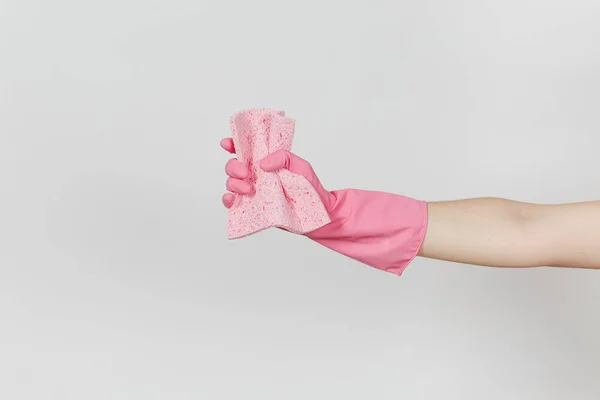Il primo piano di mano femminile in guanti rosa tiene e stringe il tovagliolo assorbente rosa per pulire e lavare piatti isolati su sfondo bianco. Concetto di forniture di pulizia. Copia spazio per pubblicità — Foto Stock