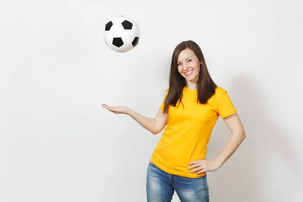 Bella europea giovane allegra donna felice, tifoso di calcio o giocatore in uniforme gialla vomitare pallone da calcio isolato su sfondo bianco. Sport, calcio, salute, stile di vita sano . — Foto Stock